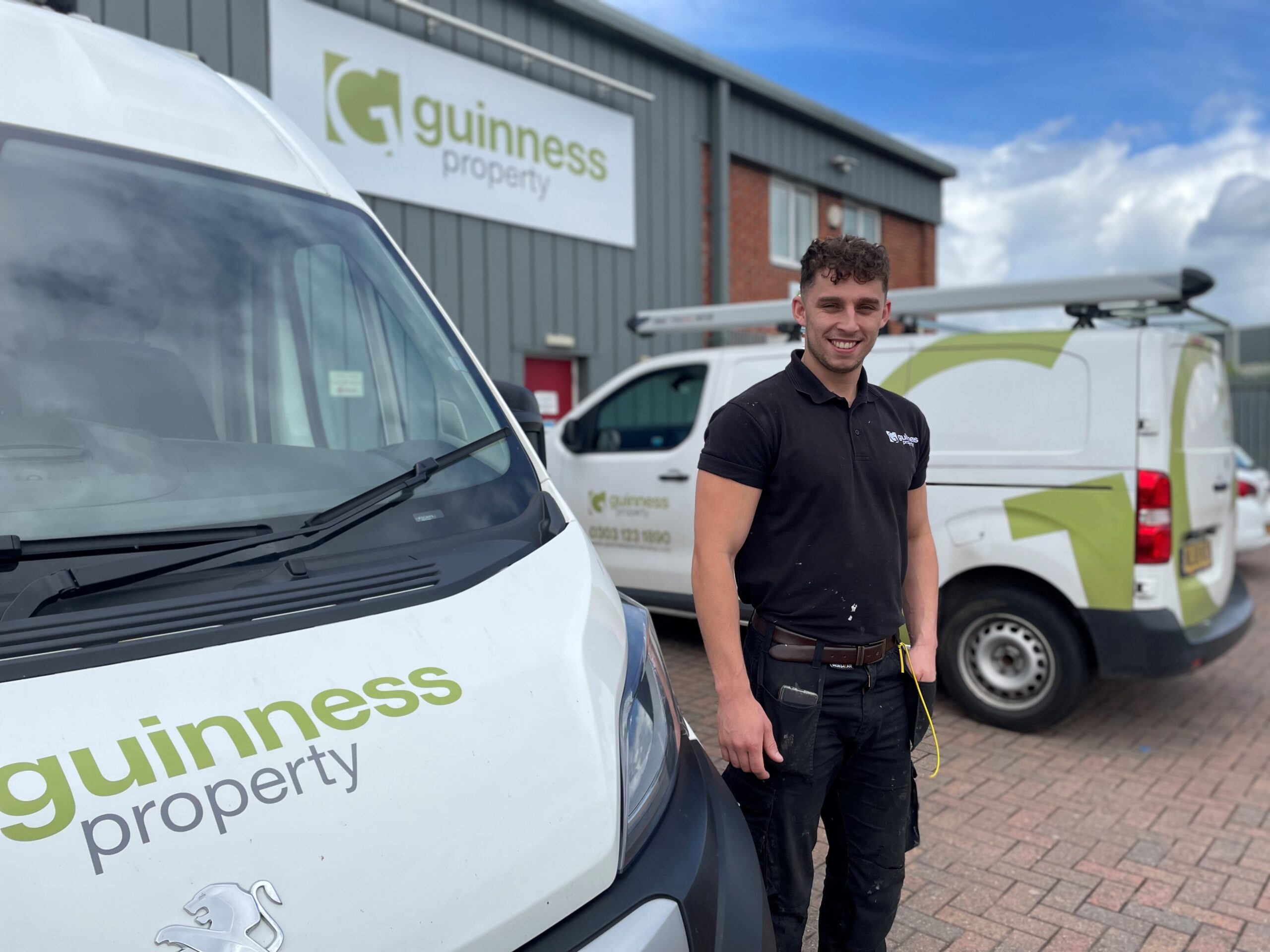 A photograph of Joe Green outside Guinness Property next to the company vans he uses to go from job to job
