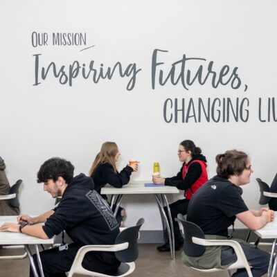 Students sat in communal space with 'Our mission: Inspiring futures, changing lives' written on the wall
